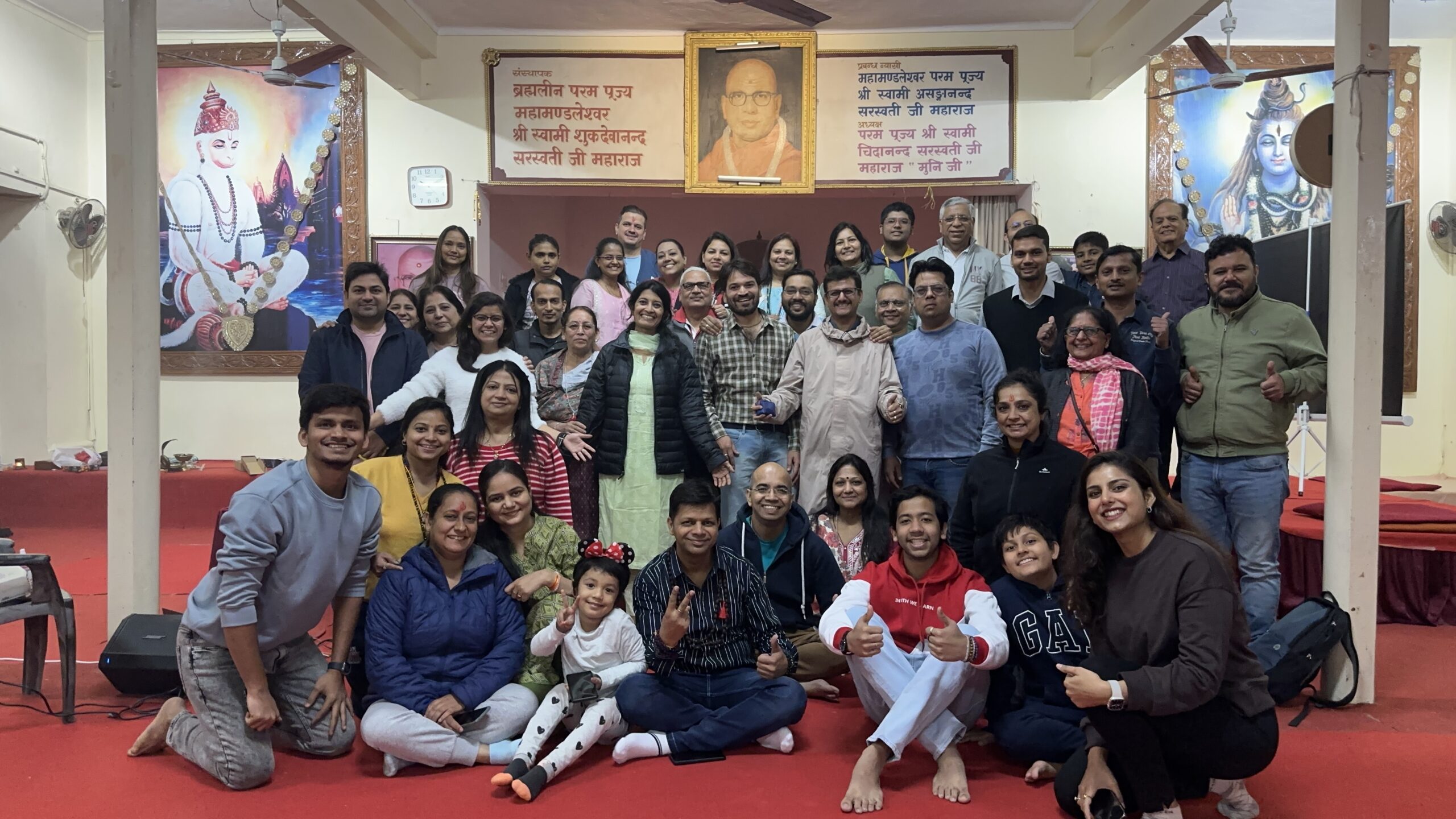 Group photo of attendees inside a decorated satsang hall